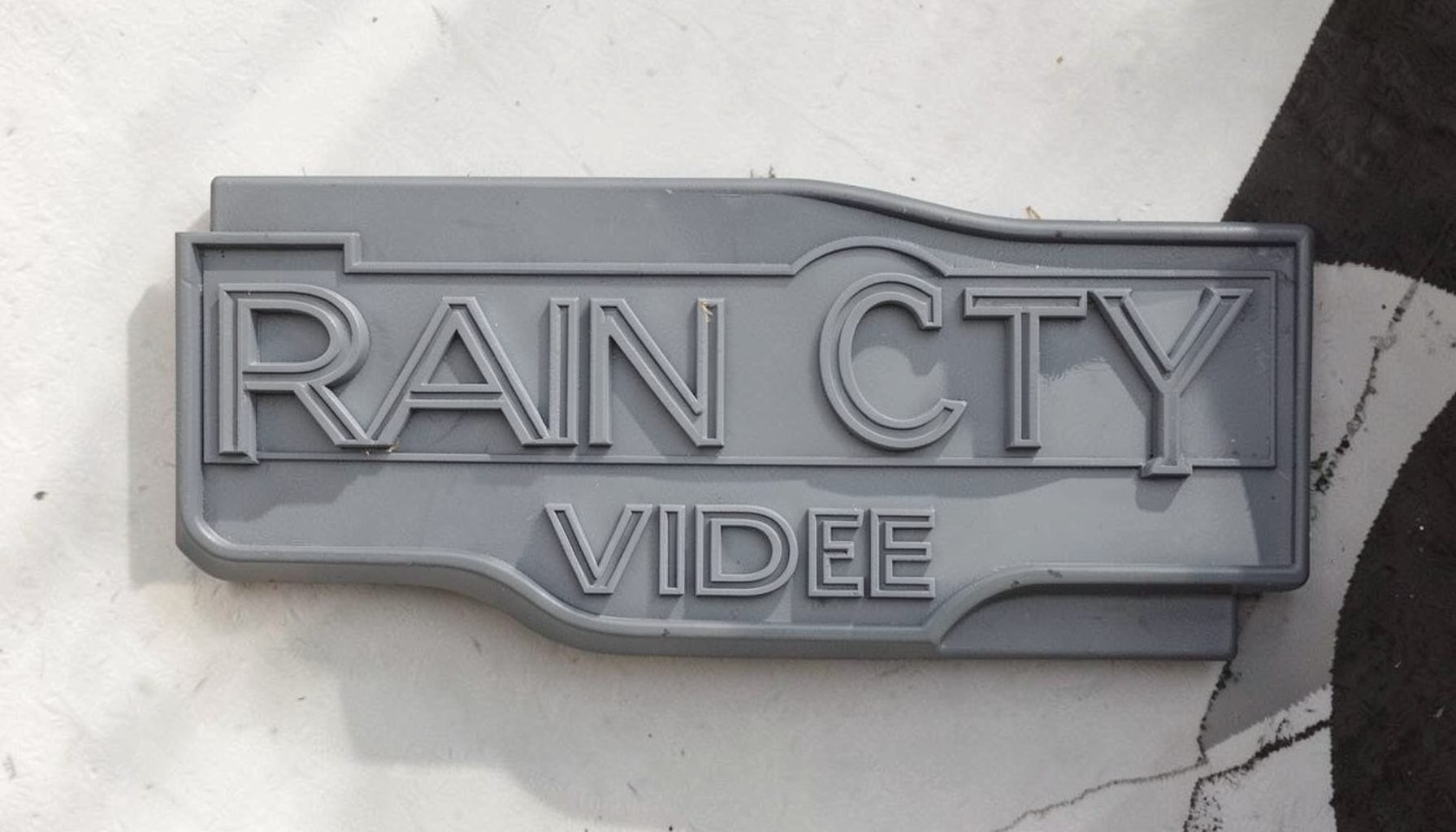 Rain City Video logo in muted slate and charcoal tones, evoking a classic independent video store marquee